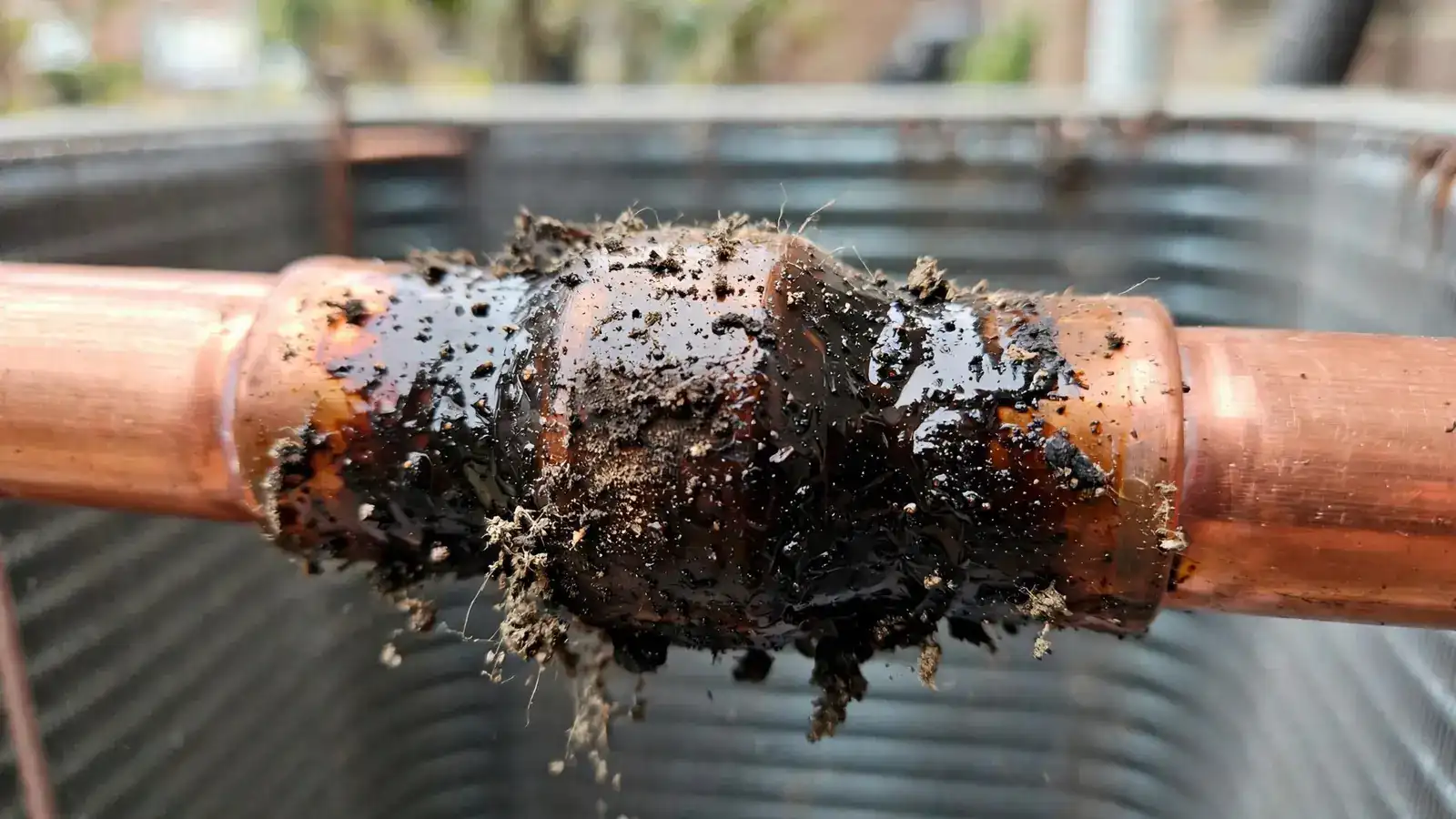 Close view of an oily stain at a copper joint on a refrigerant line